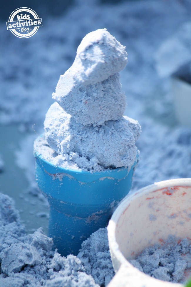 Toddler-Safe Cloud Dough that looks like scoops of ice cream in a blue plastic cone.