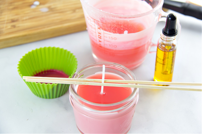 A pink crayon candle being made using soy wax and fragrance oils.