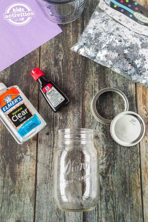 Everything you need to make a falling stars glitter jar, including the Mason jar, lid, clear glue, black dye, purple construction paper and silver star confetti. 