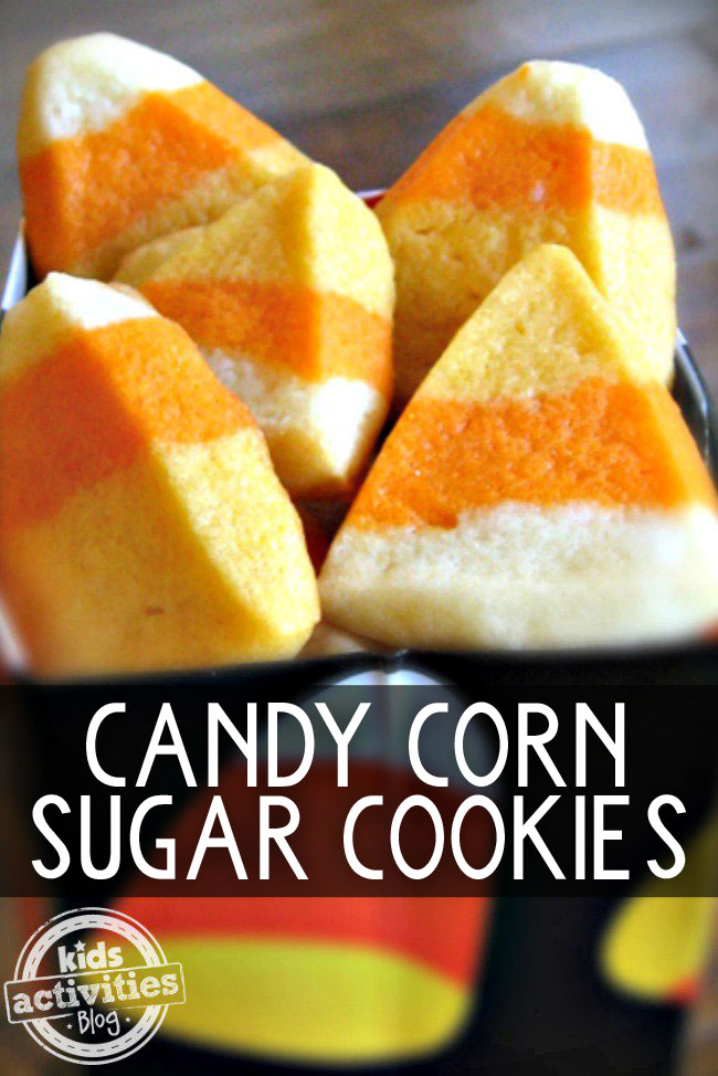 Candy corn sugar cookies in a candy corn black bowl, that are yellow, orange, and white.