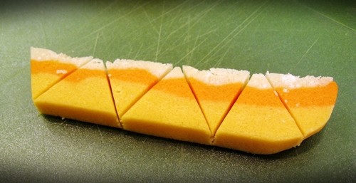 Candy corn sugar cookie dough that is cut into triangles and yellow, orange, and white