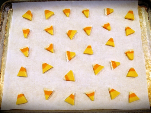 The orange, yellow, and white candy corn looking sugar cookies on parchment paper.