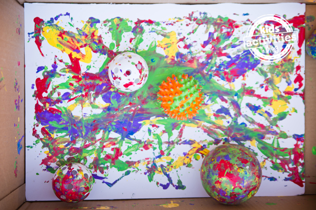 Painting With Balls project for toddlers and preschoolers - canvas in the bottom of the cardboard box with paint-filled balls and trails of color.