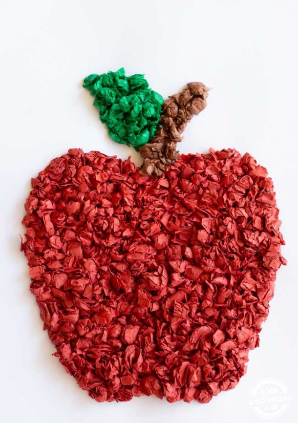 Red, green, and brown tissue paper apple on white cardstock. 
