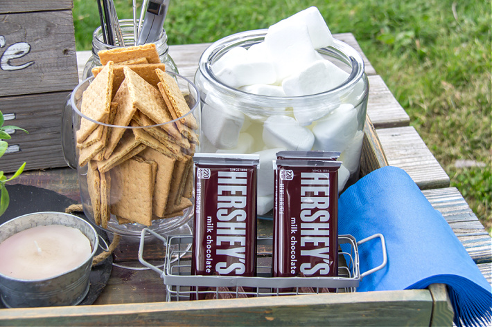 Hershey's chocolate bars, marshmallows and Graham crackers in containers for an outdoor movie night with s'mores.