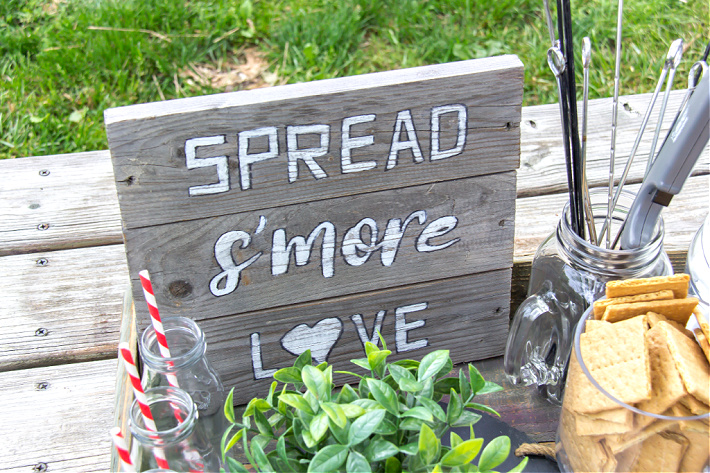 A handmade wood spread s'more love sign on a s'mores tray for a movie night.