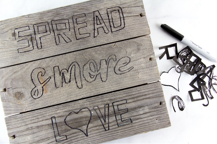 A handmade spread s'more love sign being made with printable letters and paint on wood.