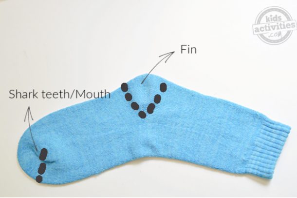 A blue sock used to make shark puppet and the areas are marked for cutting