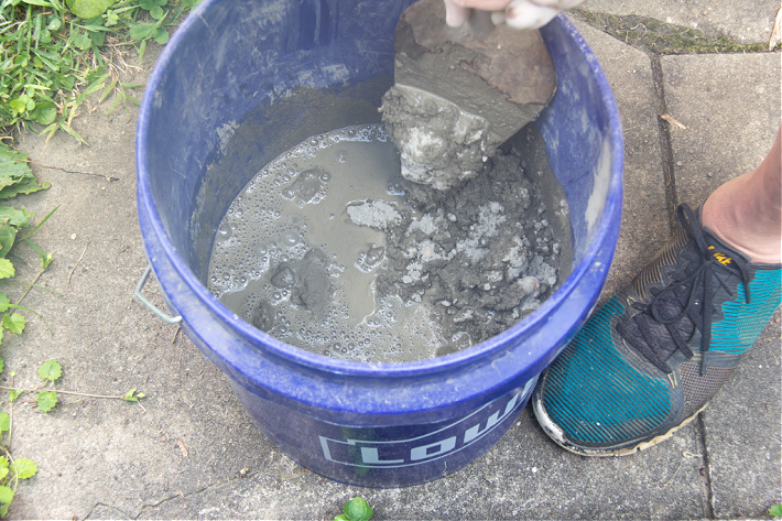 Mixing fast-setting concrete mix in a bucket with water.
