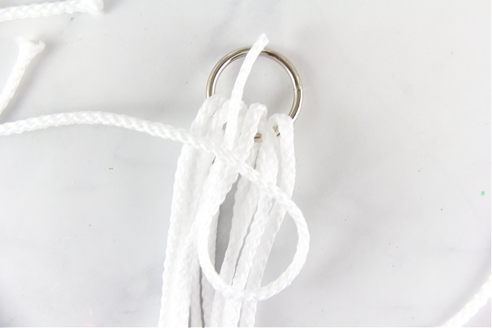 Macrame cord wrapped over a metal ring with a loop for securing it.