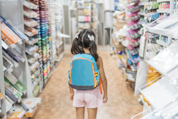 Child on the aisle of school supplies for back to school shopping wearing backpack