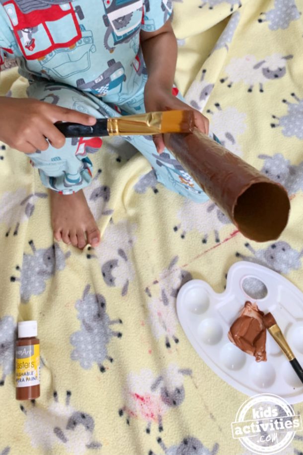 Toddler painting an empty paper roll for preschool craft to make snake