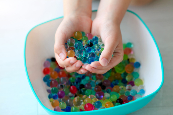 Water bead sensory play - Kids Activities Blog - child with water beads in hands over large plastic bowl
