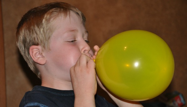 boy blowing up balloon