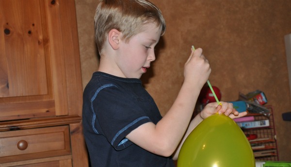 boy putting glow stick in balloon