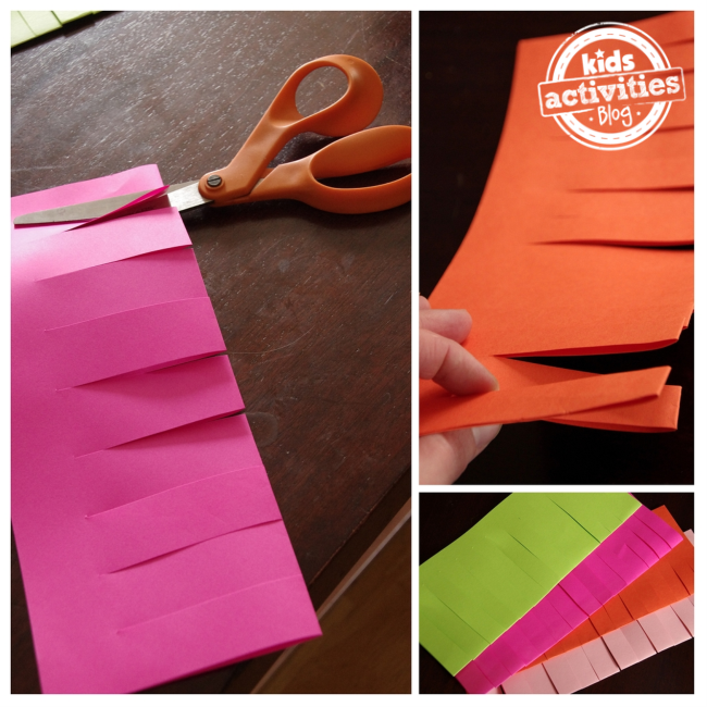Craft paper punches make mini paper lanterns that are being cut by orange scissors. There are 4 flameless paper lanterns with the colors: pink, orange, white, and green.