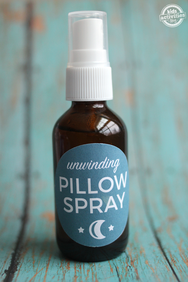 lavender pillow spray diy in a glass bottle with white cap and blue label with a moon and stars on it.