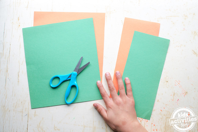  make an Irish flag craft step one - cut off 1/3rd of each of the green and orange paper