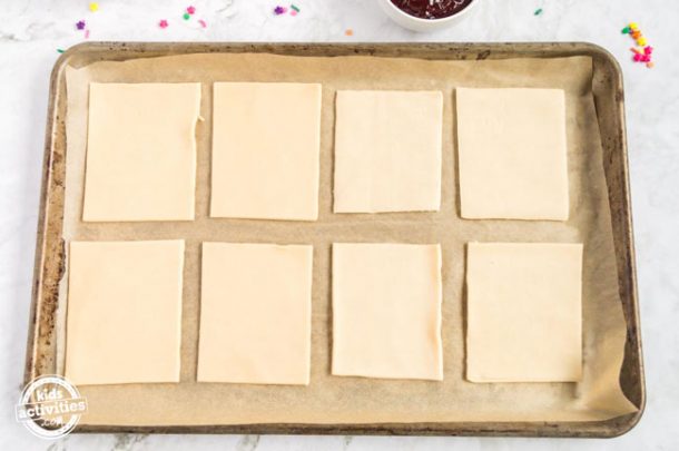 Eight rectangles of pie crust assembled on parchment paper on a baking sheet.