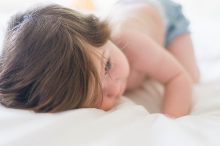 What age does a baby sleep through the night?  Baby shown with eyes open but tired.