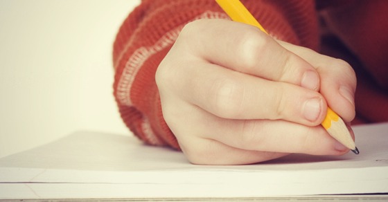 Wrong way to hold a pencil - common incorrect position kids often use - four fingers clench the pencil instead of three - shown writing improperly on notebook paper