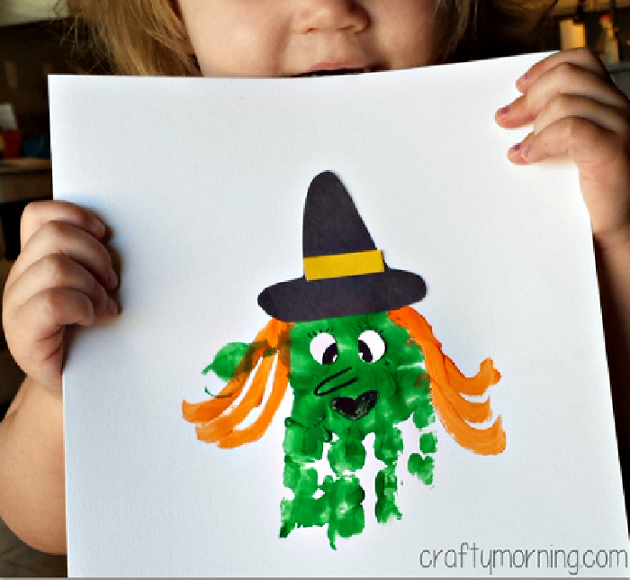 handprint halloween witch with a black witch hat and green handprint face