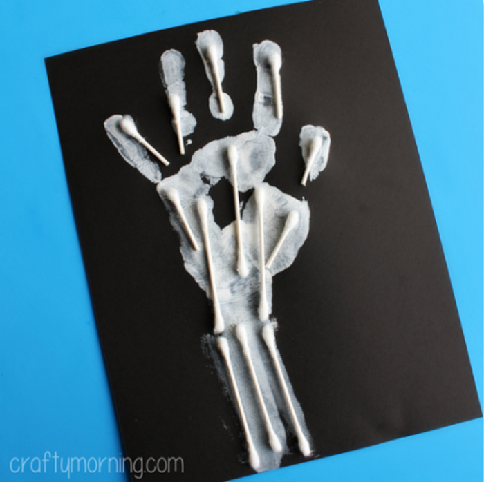 white handprint on black paper with q-tips where bones would be
