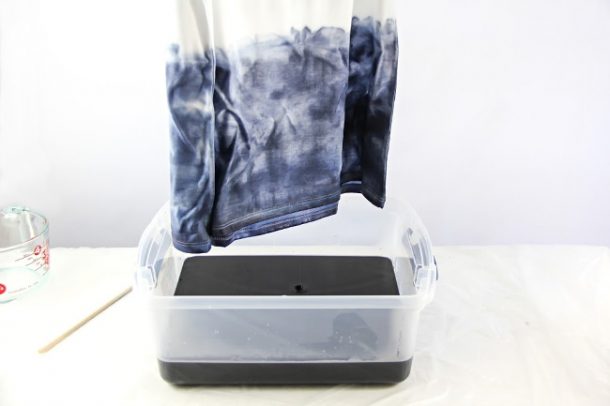a tshirt being dip dyed blue in a plastic tub