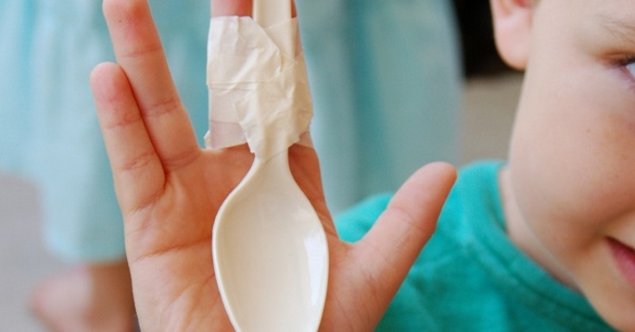 stem activities for kids that involves a child have an upside down spoon to his fingers with masking tape.