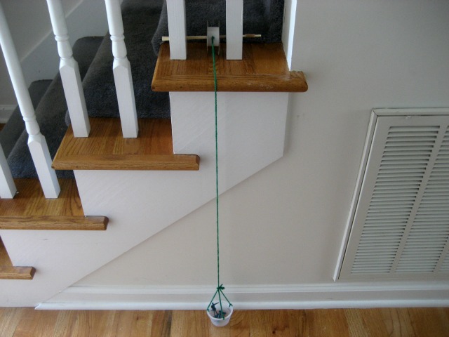 Our homemade pulley system - Science for Kids: Make a Pulley - plastic basket hanging off stairs on string 