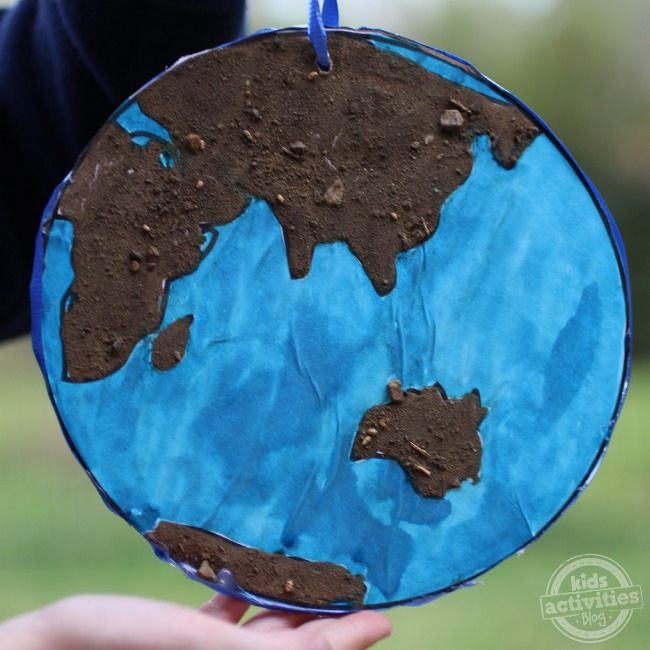 Earth day art that looks like the world, the ocean is blue, and land masses are covered with dirt.