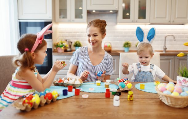 A family using various Easter egg designs to paint eggs wearing bunny ears.