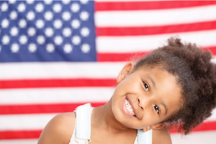 Memorial Day Celebration for Kids including Crafts - Kids Activities Blog - preschooler in front of an American flag
