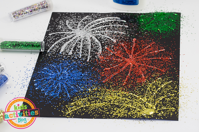 fireworks art using glitter and glue - Kids Activities Blog - in process showing glitter of 4 colors on top of glue on black paper