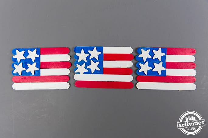 American Flag Craft for Kids perfect for Memorial Day - Kids Activities Blog - three popsicle stick USA flag crafts on gray background